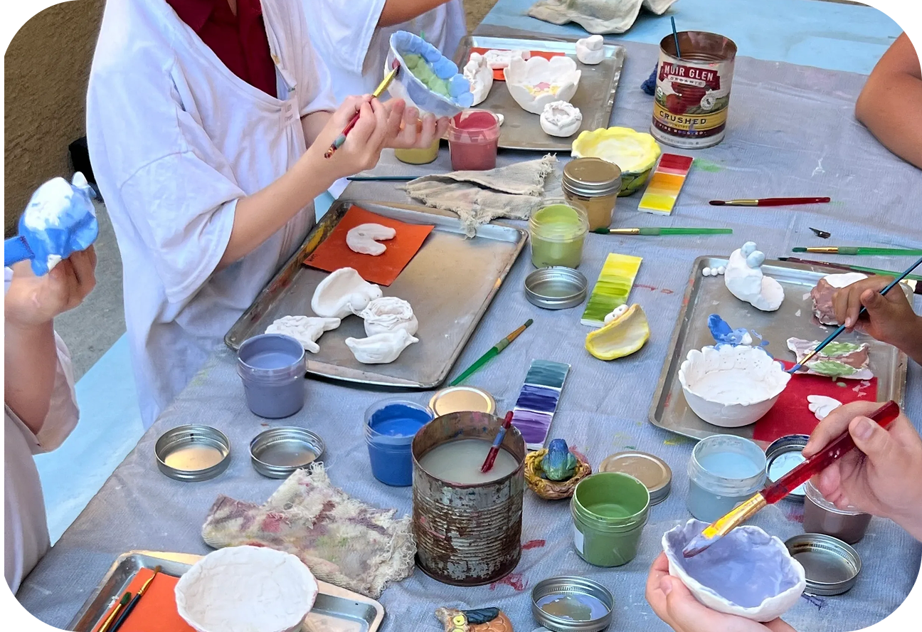 Children painting plaster models at table.
